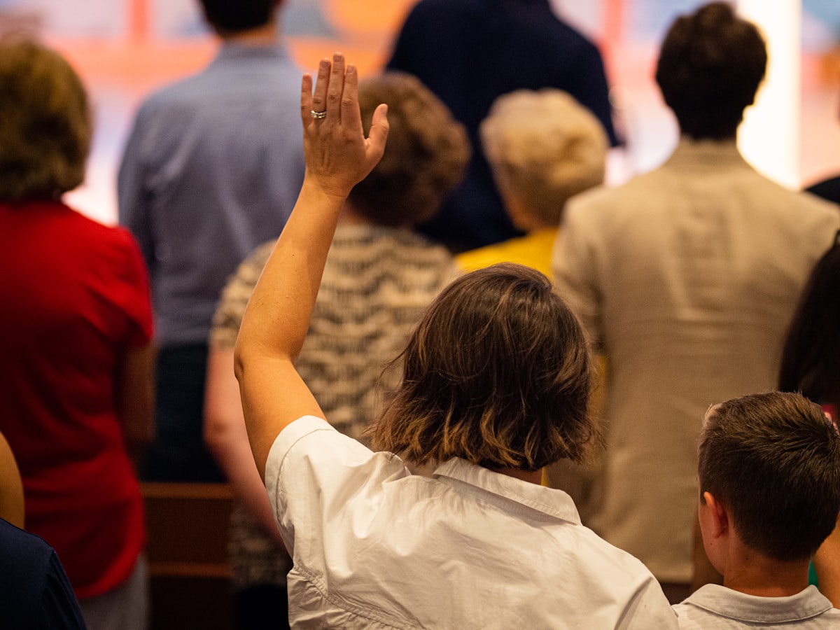 Pessoa com a mão levantada adorando no culto